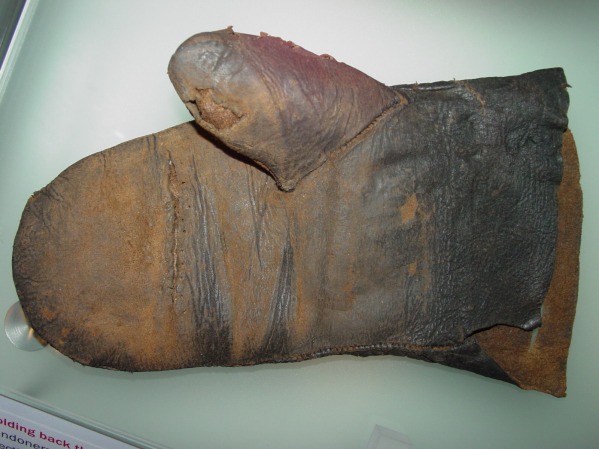 Leather glove, 15th c. from Bankside Southwark. The cutout for the thumb stall is teardrop shaped, there is a repaired tear across the mitten.